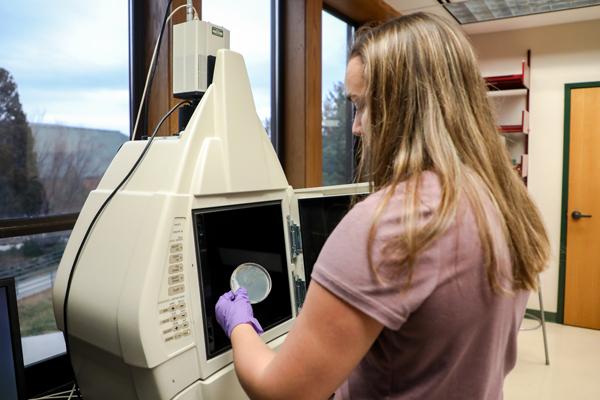 Student putting a petri dish in a machine