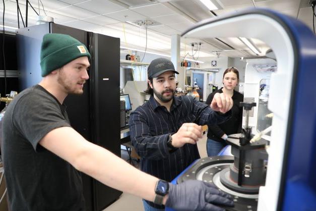 Three students using engineering lab equipment